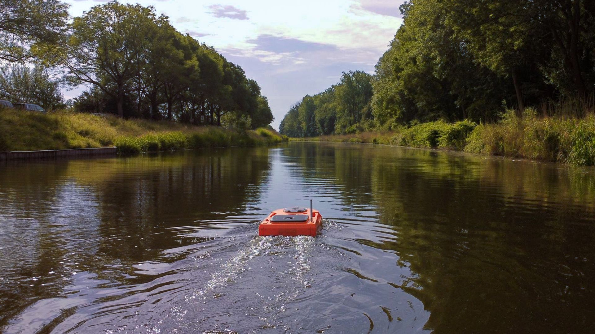 Een oranje boot drijft op een rivier omringd door bomen