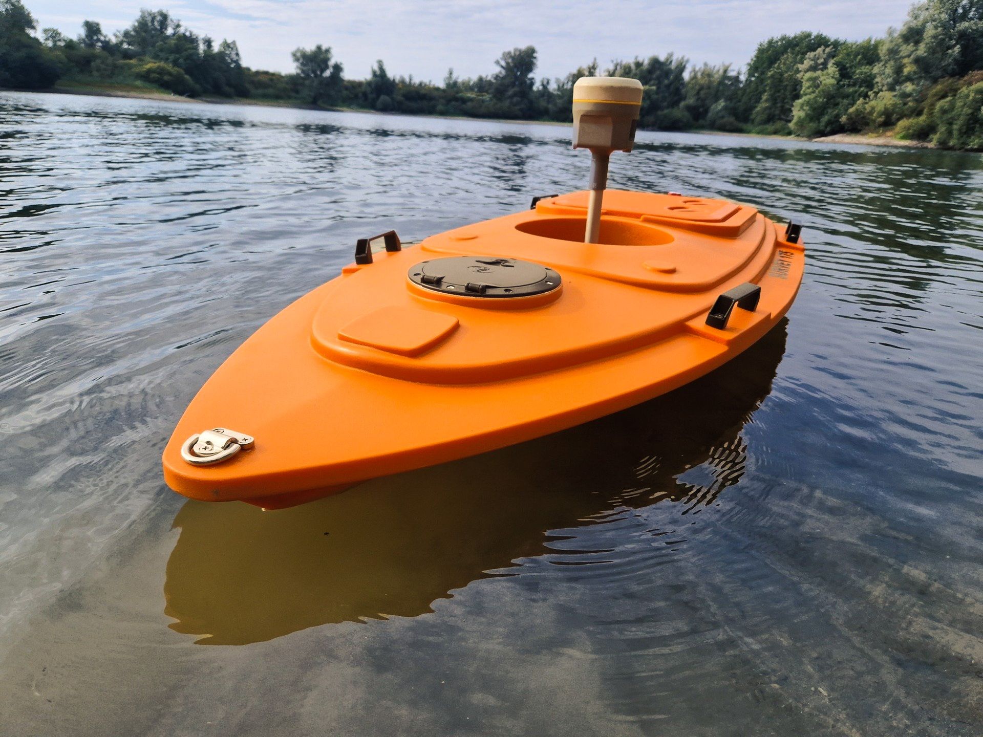 Een kleine oranje boot drijft op een watermassa