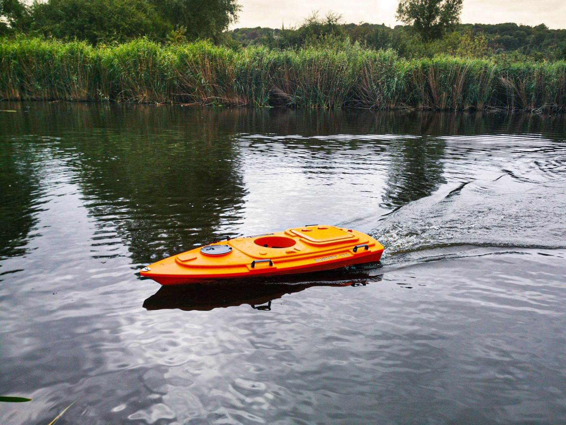Een oranje kajak drijft op een rivier.