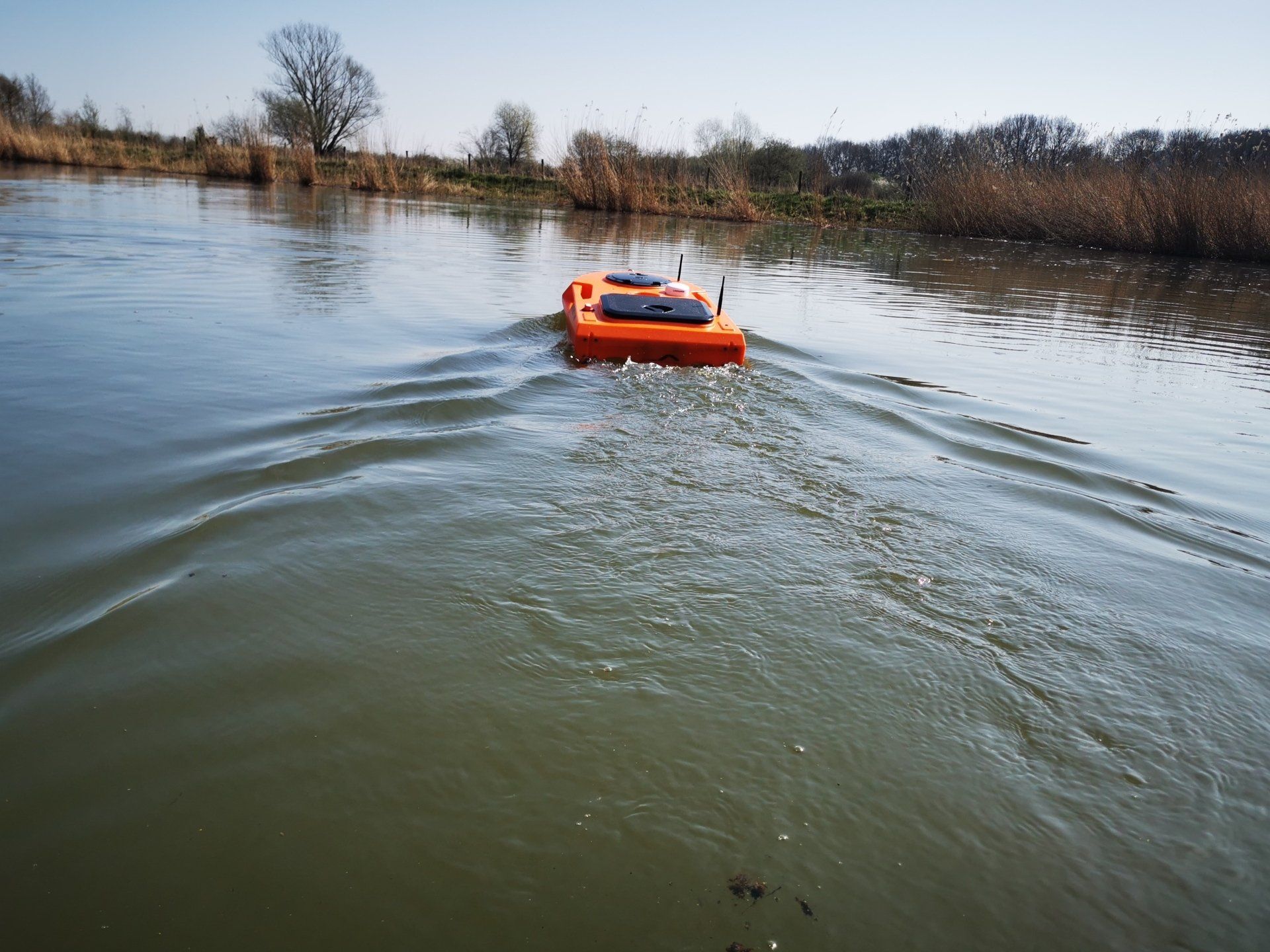 Een kleine oranje boot drijft op een watermassa.