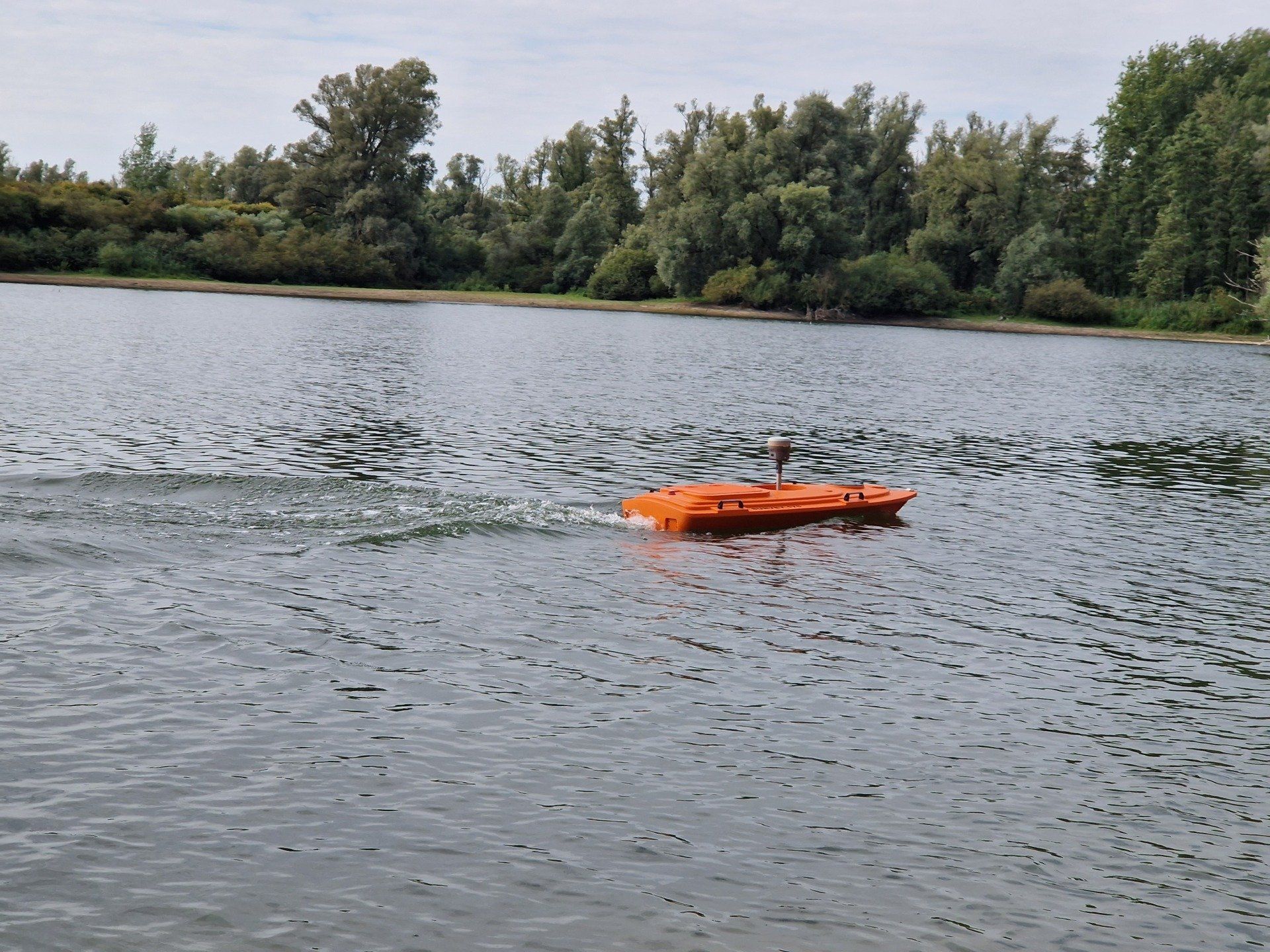 Een kleine oranje boot drijft op een meer