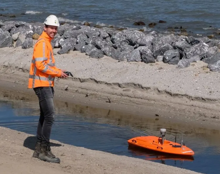 Een man speelt met een boot met afstandsbediening op het strand.