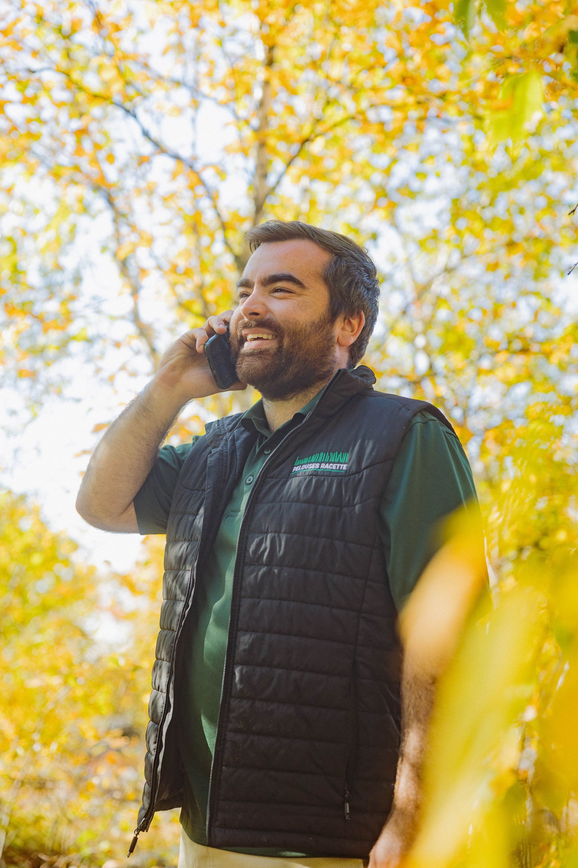 Un homme barbu parle au téléphone portable dans les bois.