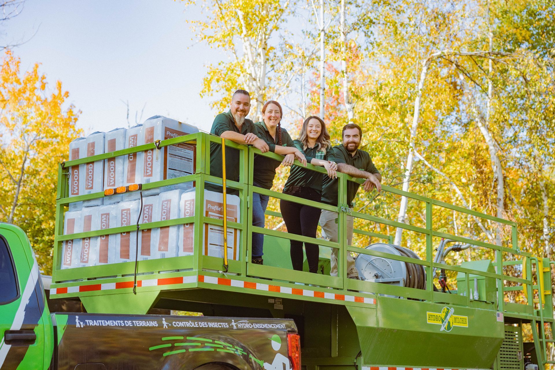 Un groupe de personnes se tient à l’arrière d’un camion vert.