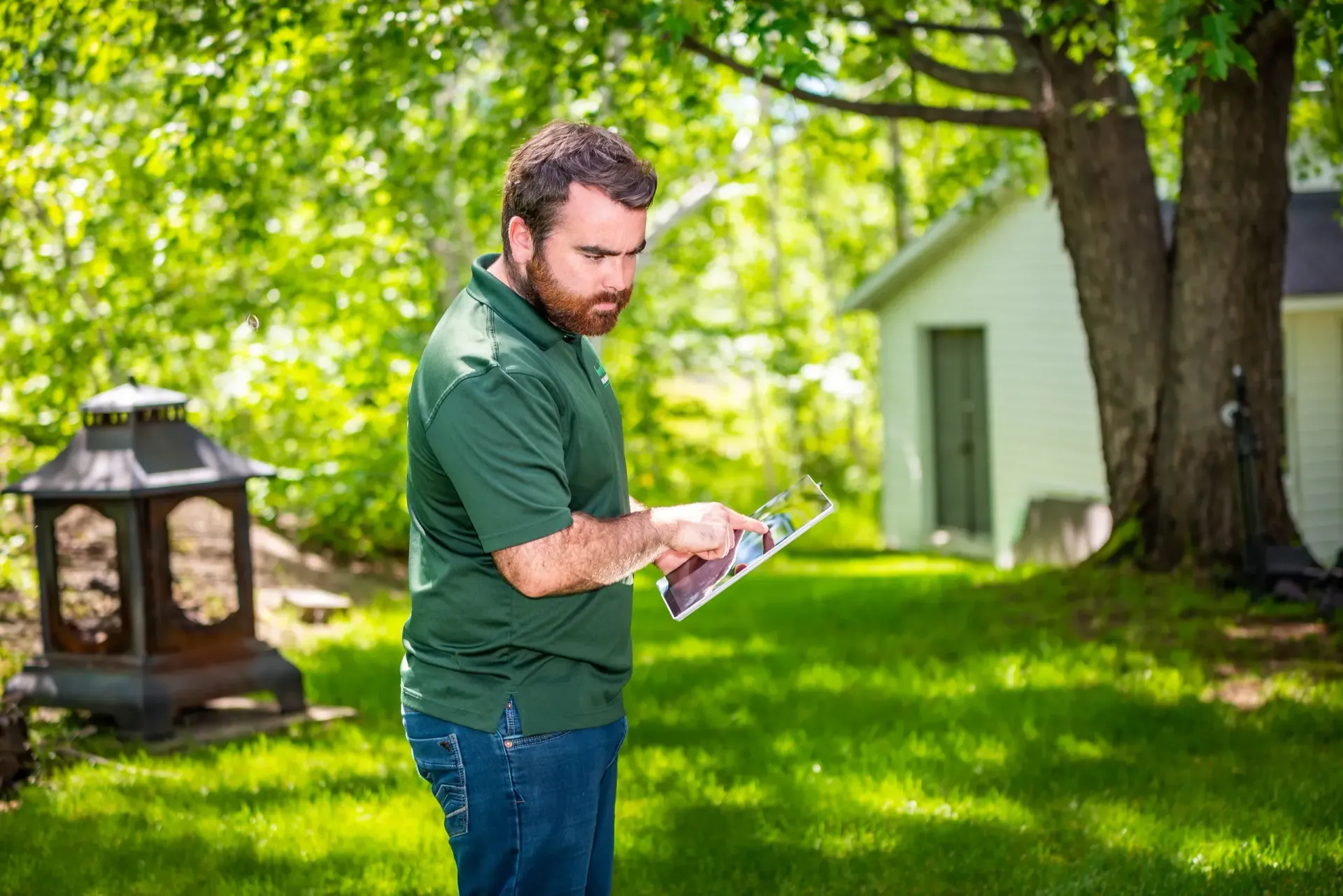 Un homme est debout dans une cour et regarde une tablette.