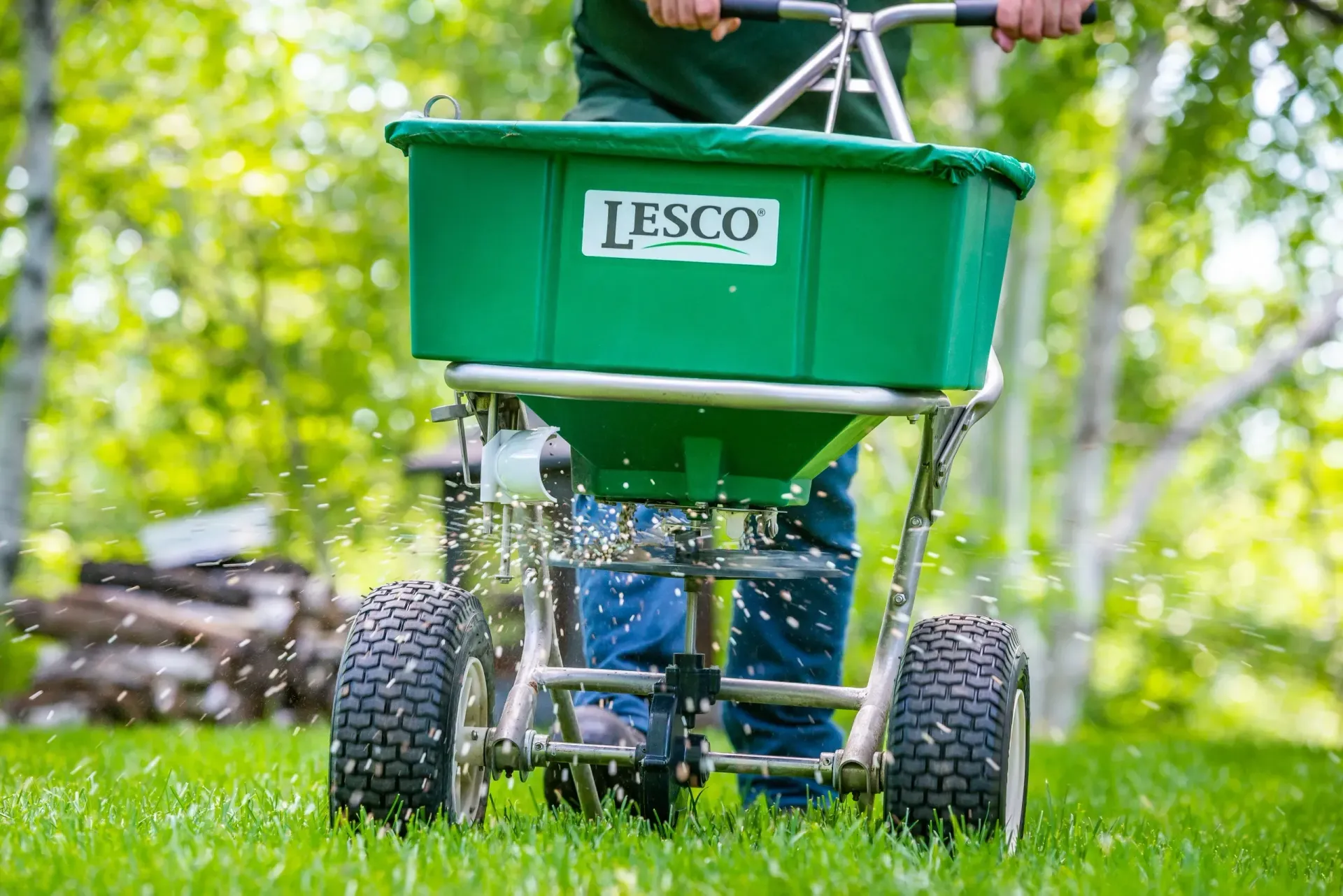 Une personne répand de l’engrais sur une pelouse verdoyante.