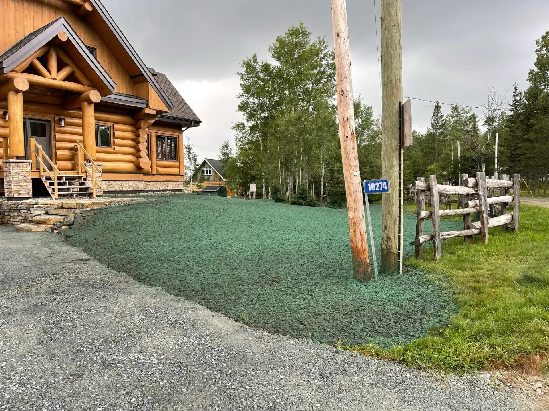 Une cabane en rondins avec une allée de gravier devant.