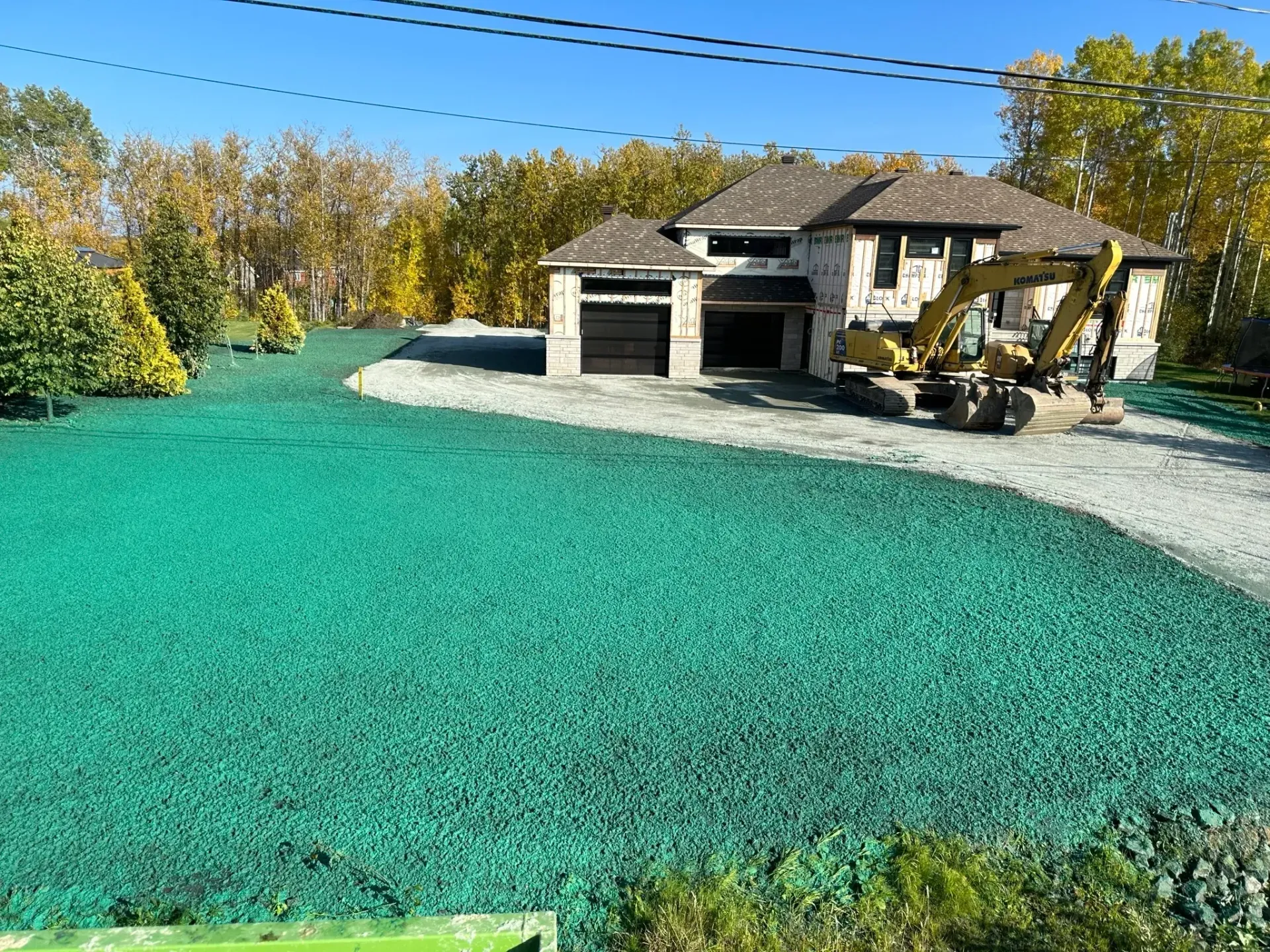 Une grande maison avec une grosse pelle garée devant.