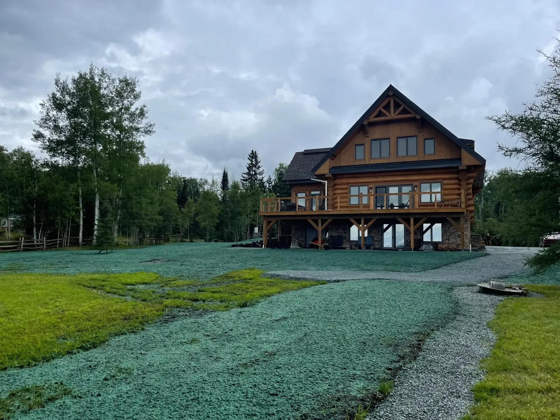 Une grande cabane en rondins se trouve au milieu d’un champ verdoyant.