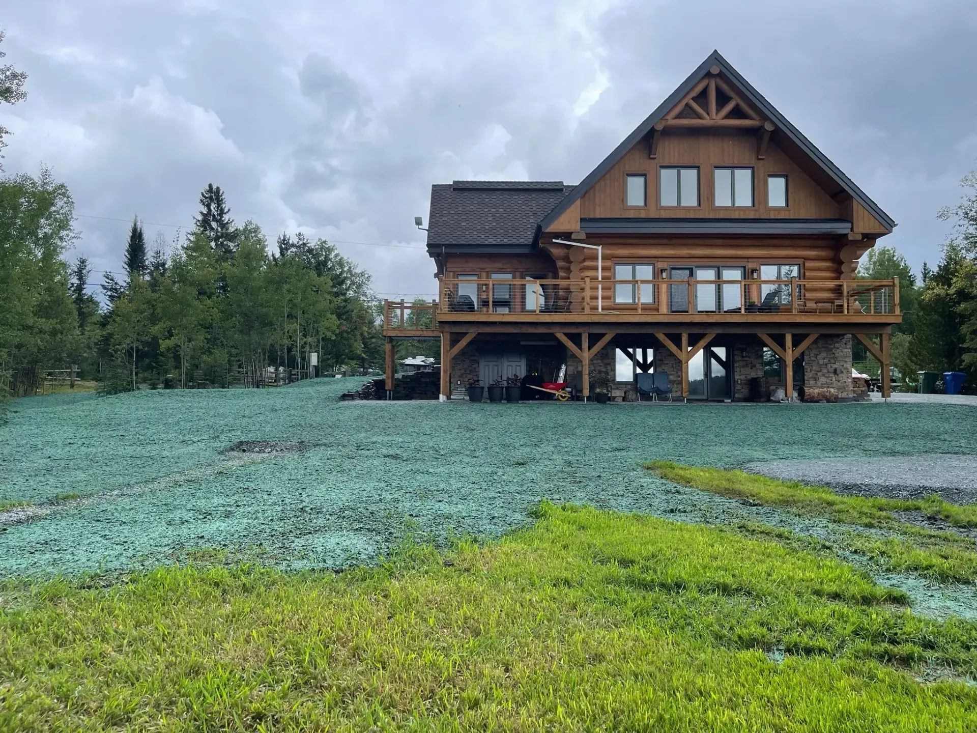 Une grande cabane en rondins se trouve au sommet d’un champ verdoyant.