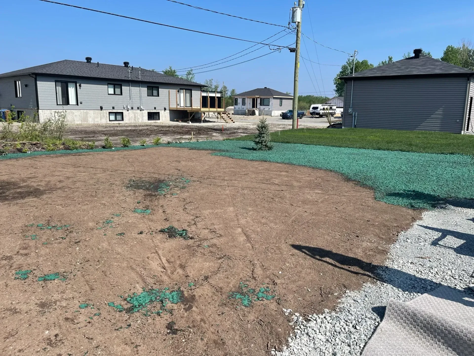 Un quartier résidentiel avec beaucoup de terre et d'herbe et une maison en arrière-plan.