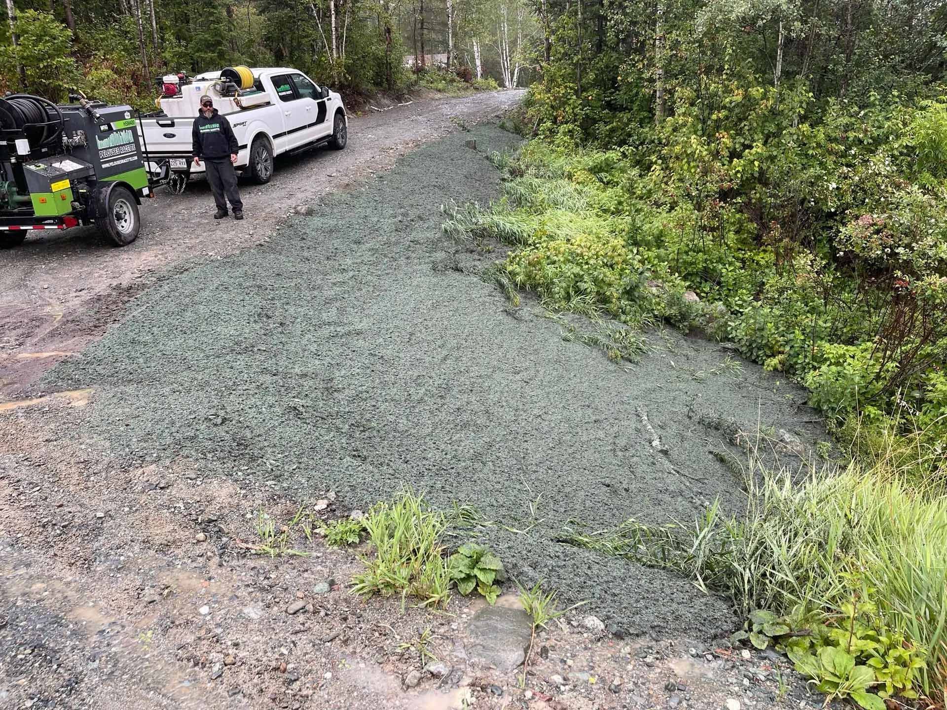 Un homme se tient à côté d’un camion sur un chemin de terre.