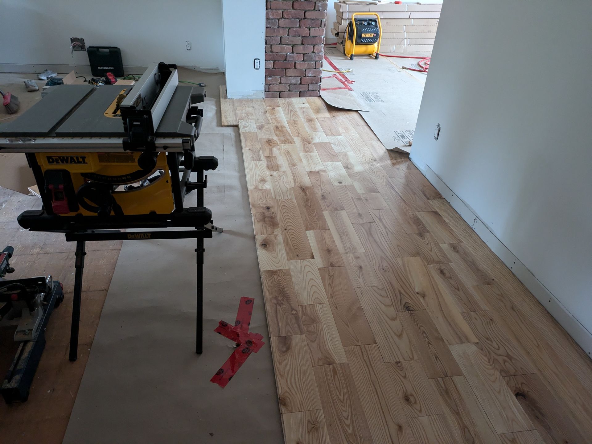 Pose de parquet en cours; table de scie à gauche, planches de bois disposées.