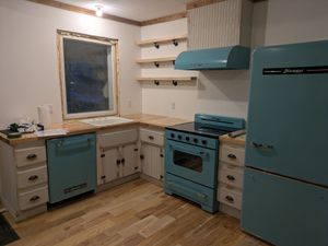 Cuisine bleue et blanche avec électroménagers, comptoirs en bois et étagères.