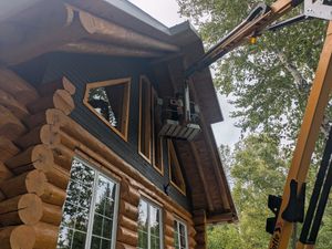 Cabane en rondins avec ascenseur ; un ouvrier peint les boiseries.