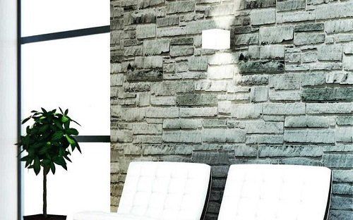 un'applique su un muro in pietra, due sedie bianche e un vaso con una pianta