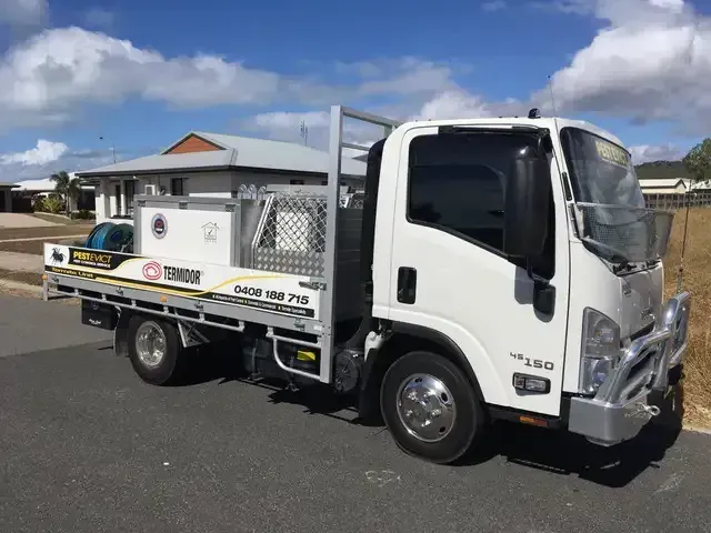 A White Truck Is Parked On The Side Of The Road Next To A House — Pest Evict Pest Control in Ayr, QLD