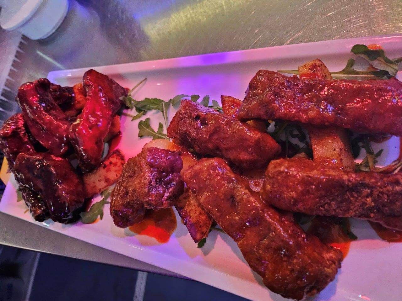 Un piatto bianco con sopra carne e salsa su un tavolo