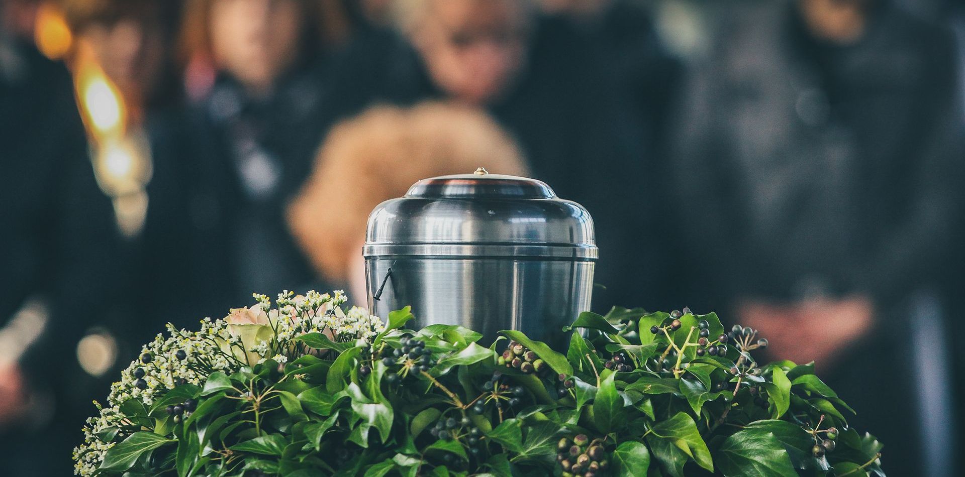 a silver urn is surrounded by flowers and leaves at a funeral