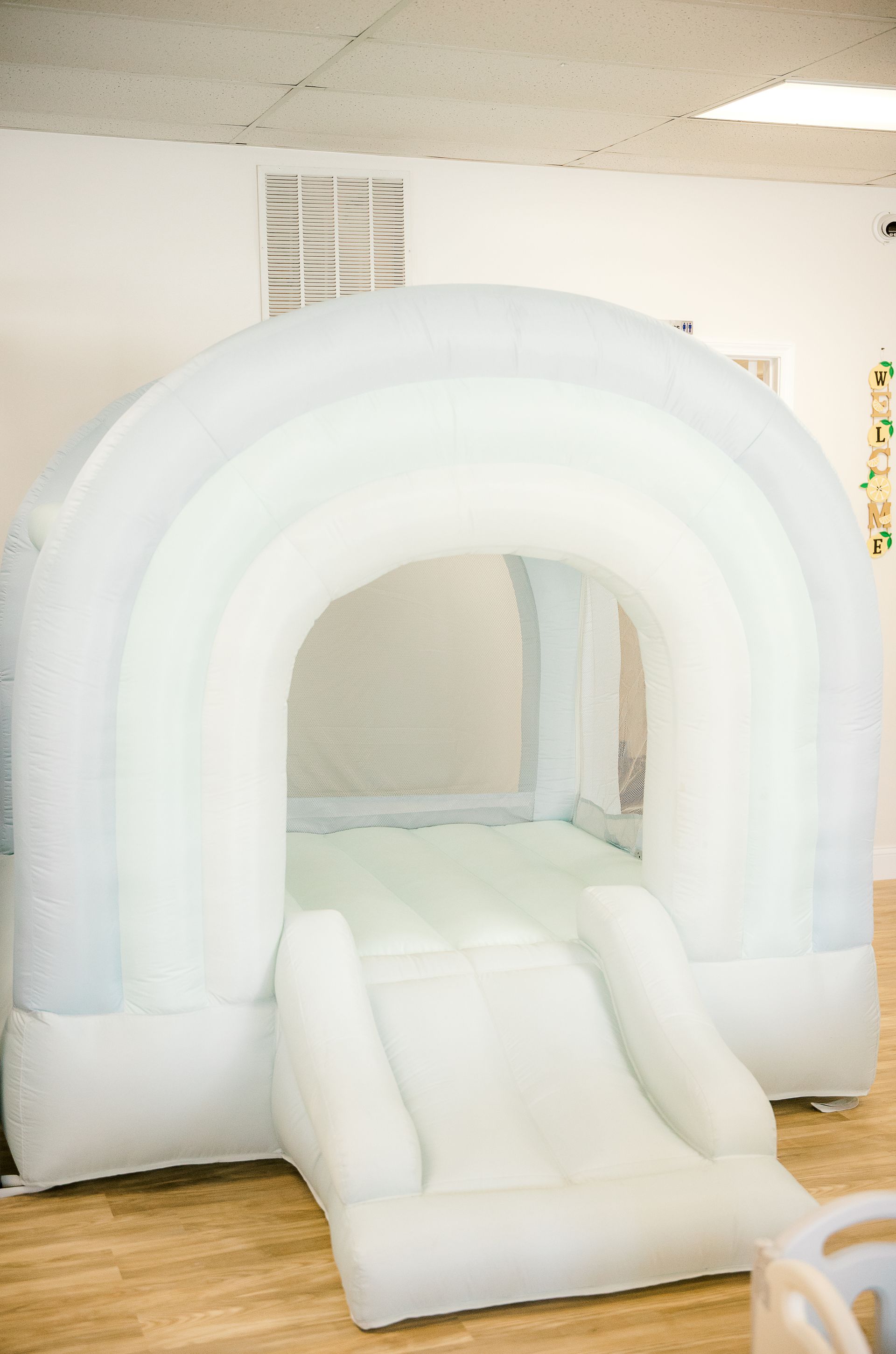 A white bouncy castle with a slide in a room.