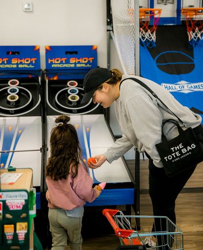 A woman and a little girl are playing Hot Shot at The Lemon Lounge Indoor Playground