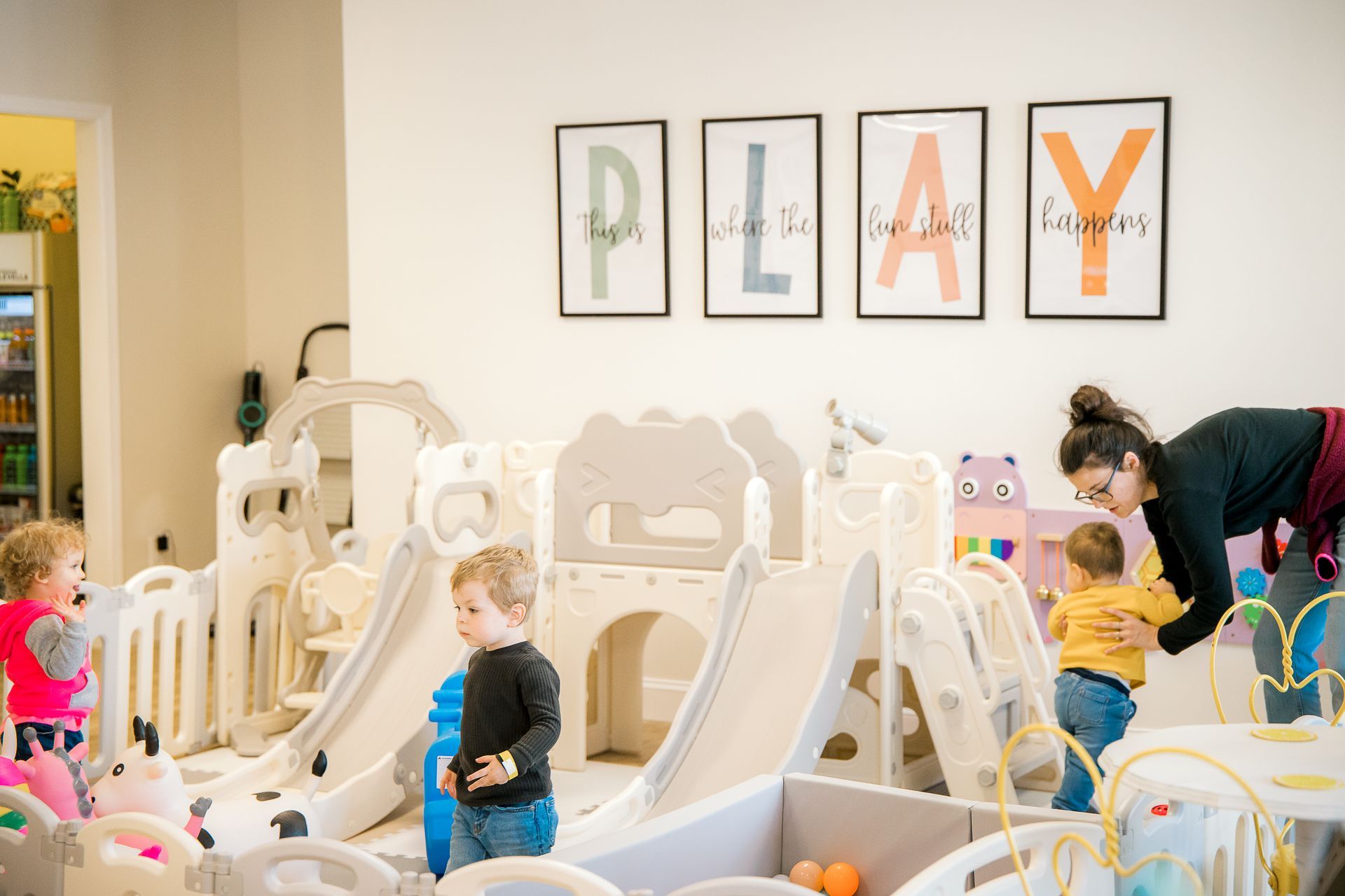 A woman is playing with three children at The Lemon Lounge Indoor Playground.