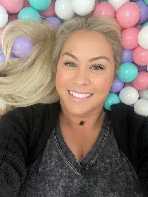 a woman is laying in a ball pit and smiling .
