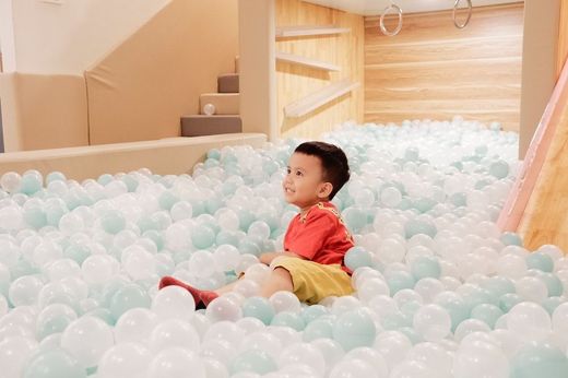 a young boy is sitting in a ball pit filled with blue and white balls .