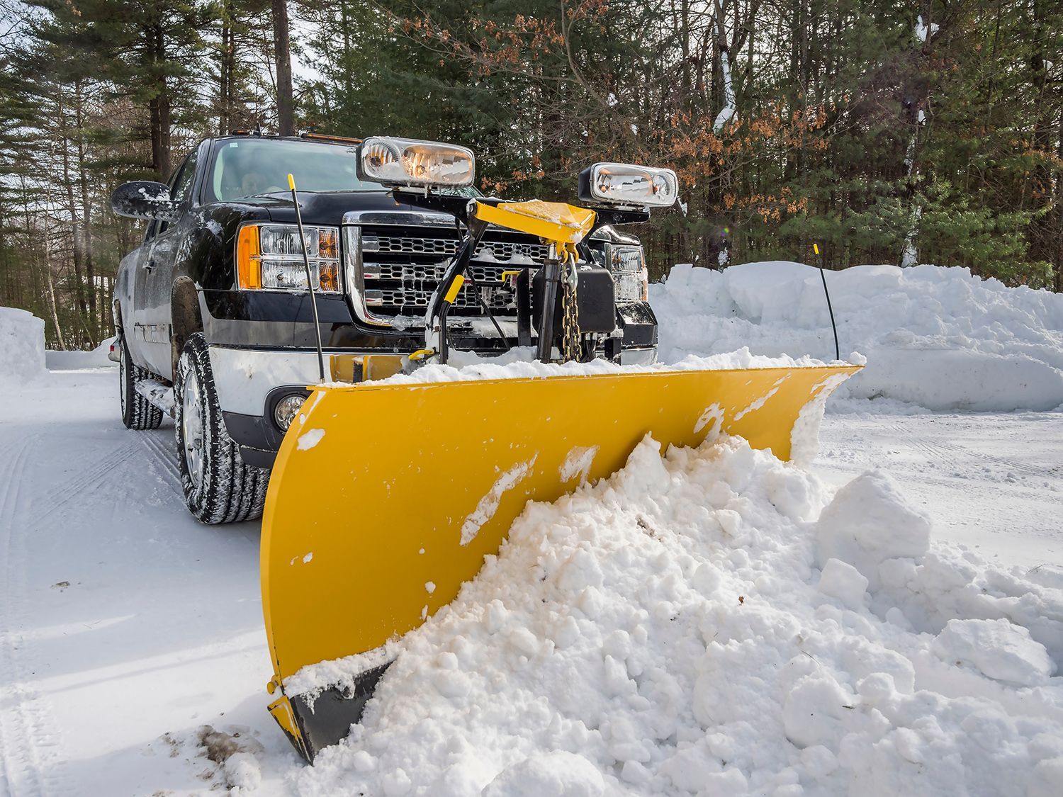 Pickup truck plowing snow off driveway.