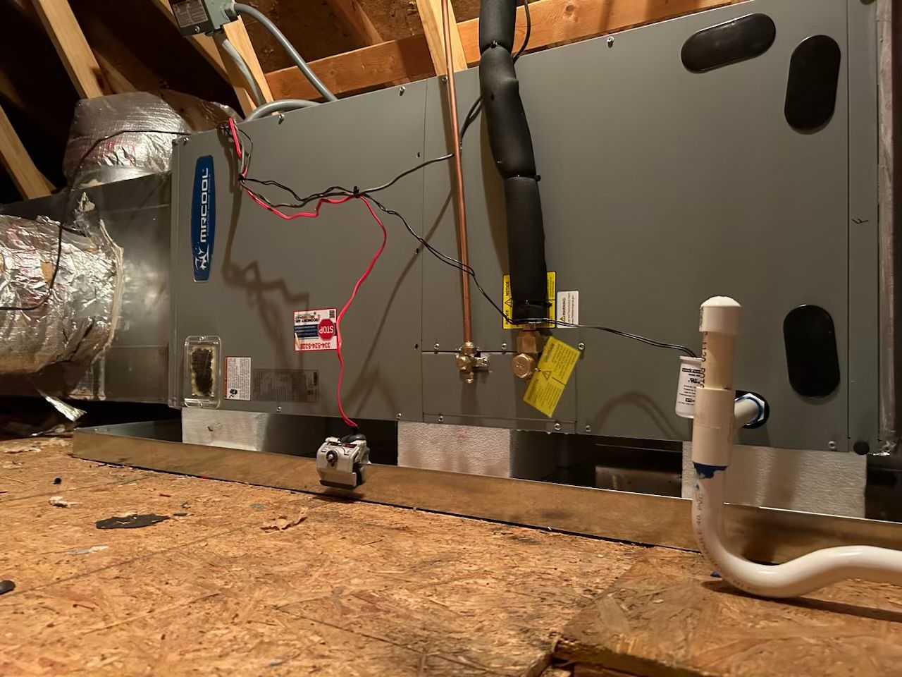 An air conditioner is sitting in the attic of a house.