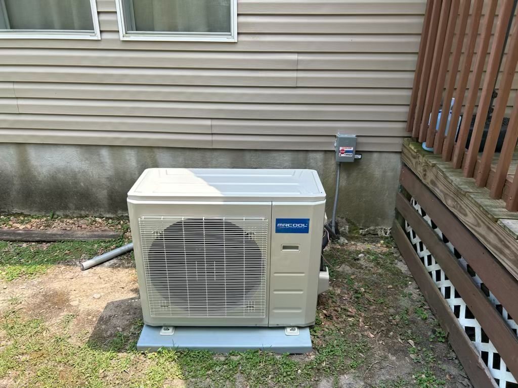 An air conditioner is sitting outside of a house next to a deck.