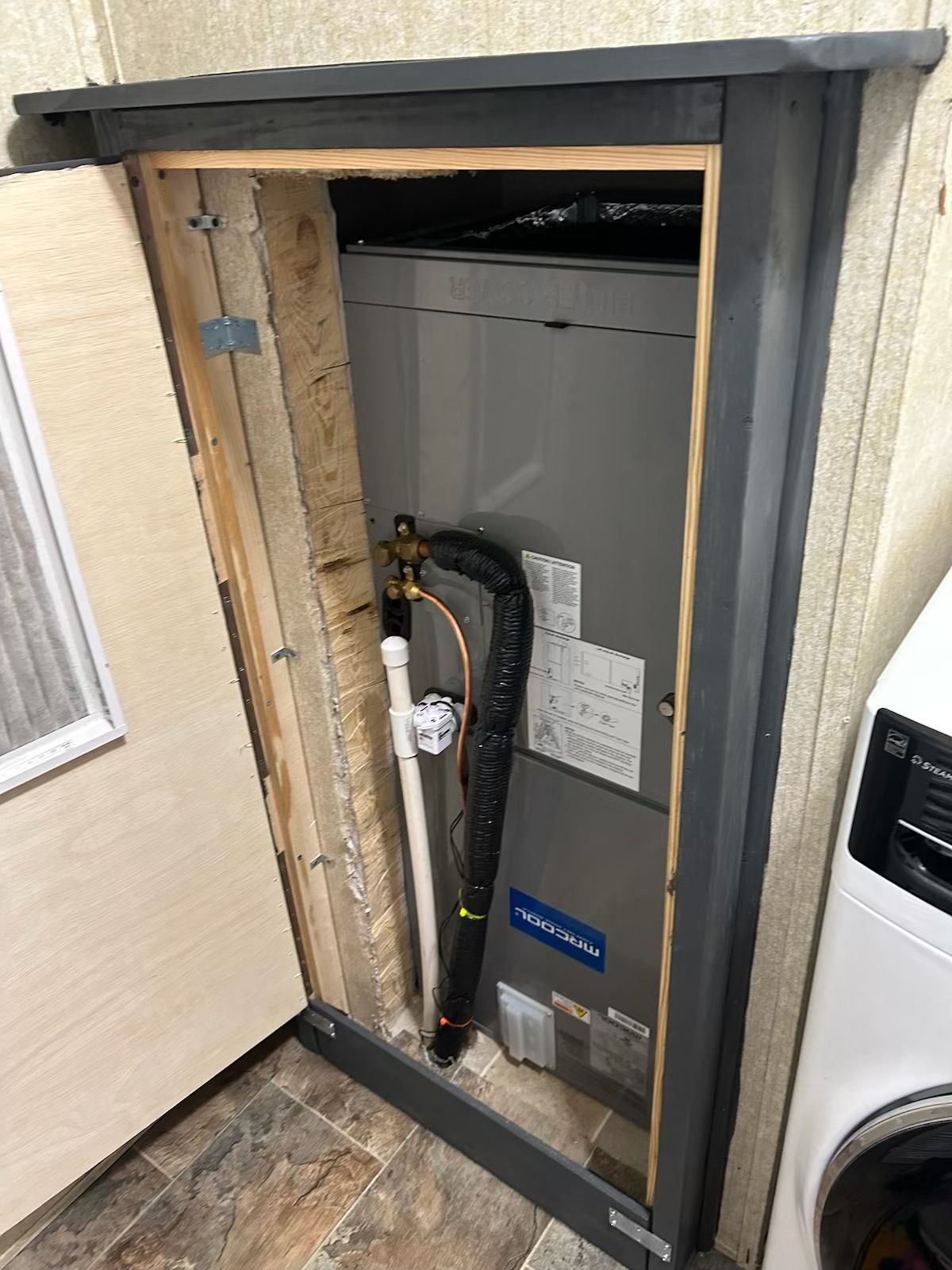 A laundry room with a washer and dryer and an air conditioner.