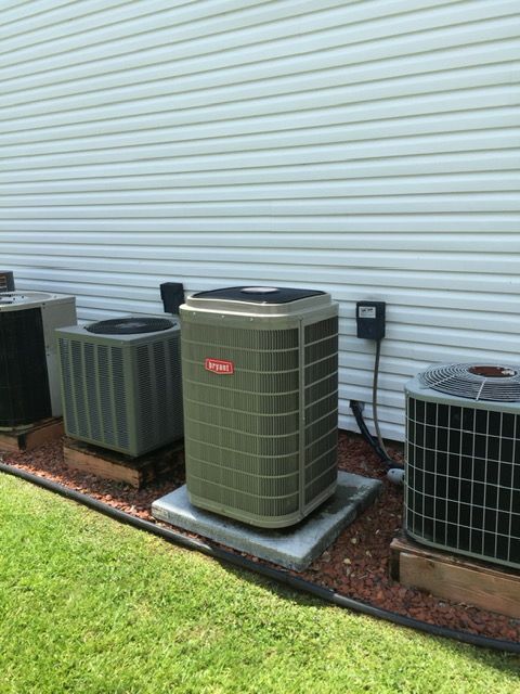 Three air conditioners are sitting on the side of a house.
