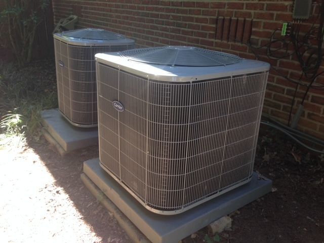 Two air conditioners are sitting outside of a brick building.