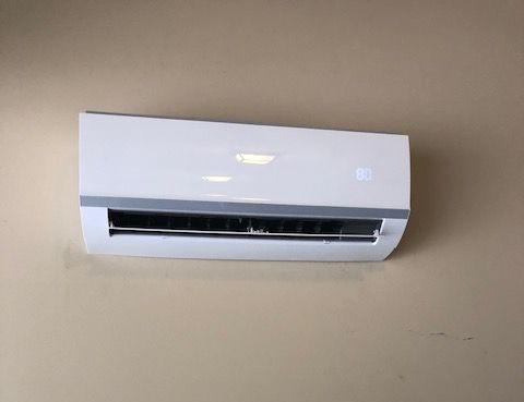 A white air conditioner is hanging on a wall.