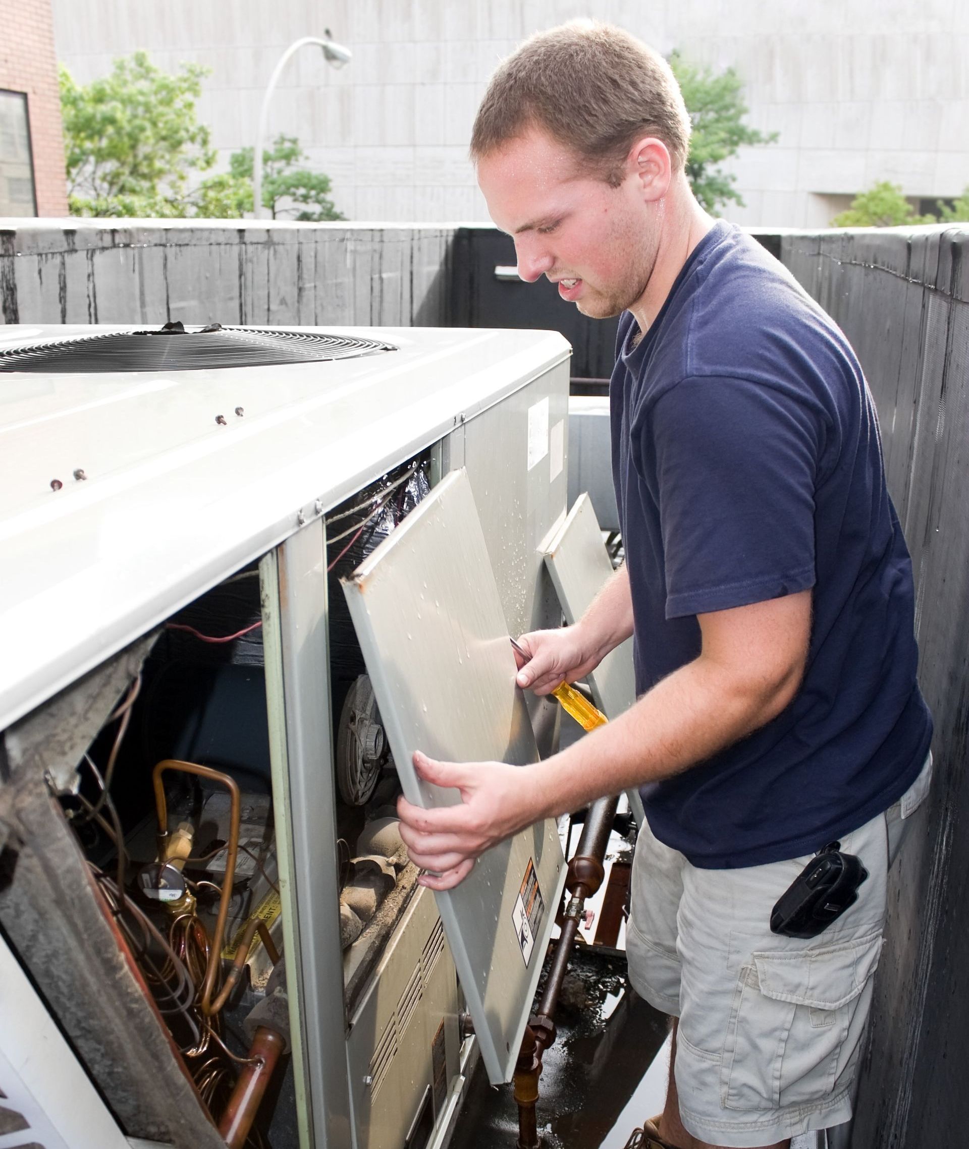 A man in a blue shirt is working on an air conditioner in Auburn Al