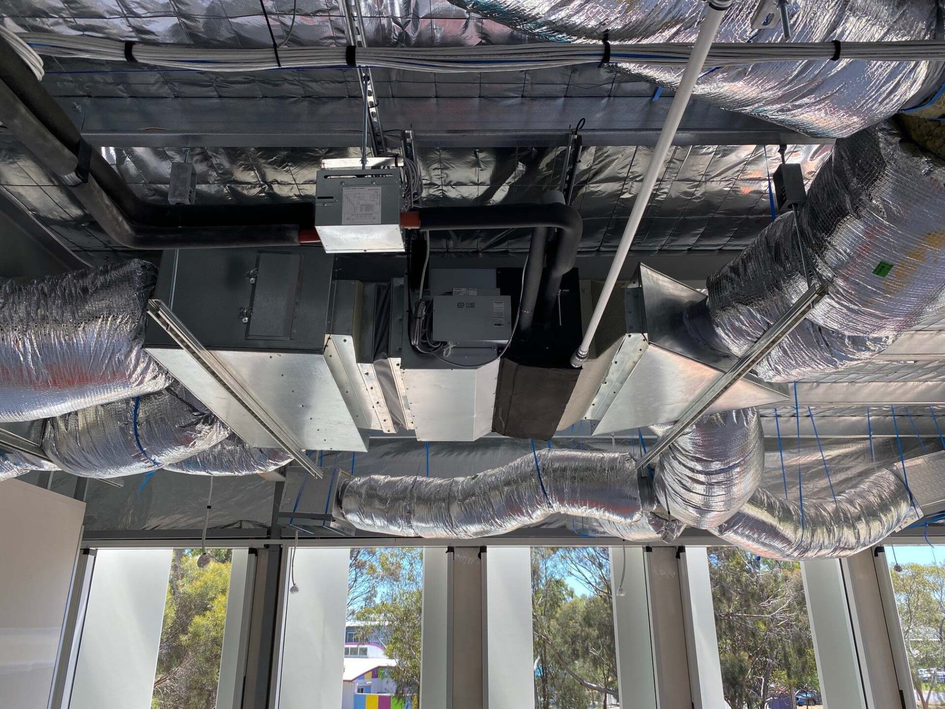 A ceiling with a lot of pipes and ducts hanging from it.