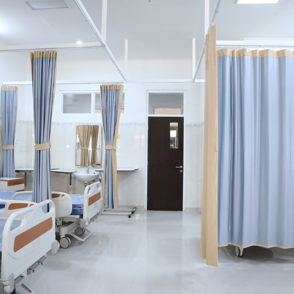 A hospital room with beds , curtains , a sink and a door.