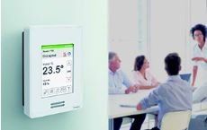 A group of people are sitting at a table in front of a thermostat.