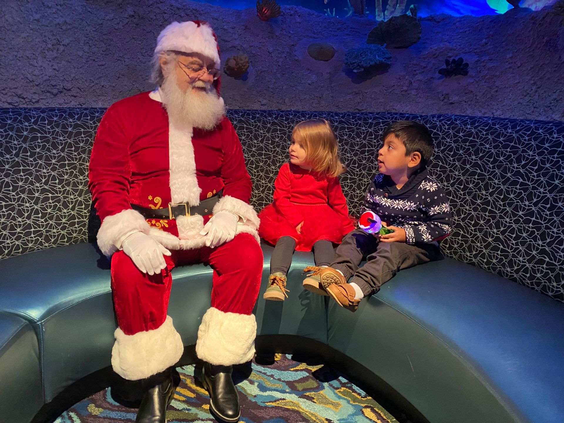 Appetizer platter at a restaurant with a large aquarium backdrop: chips, dip, fried food, and quesadillas.