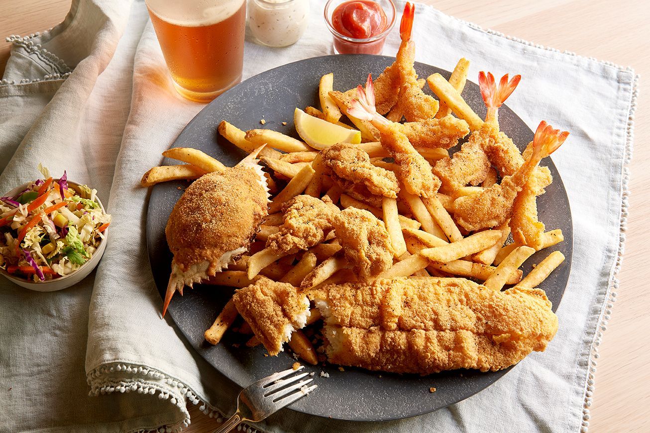 A plate of fried shrimp and french fries next to a glass of beer