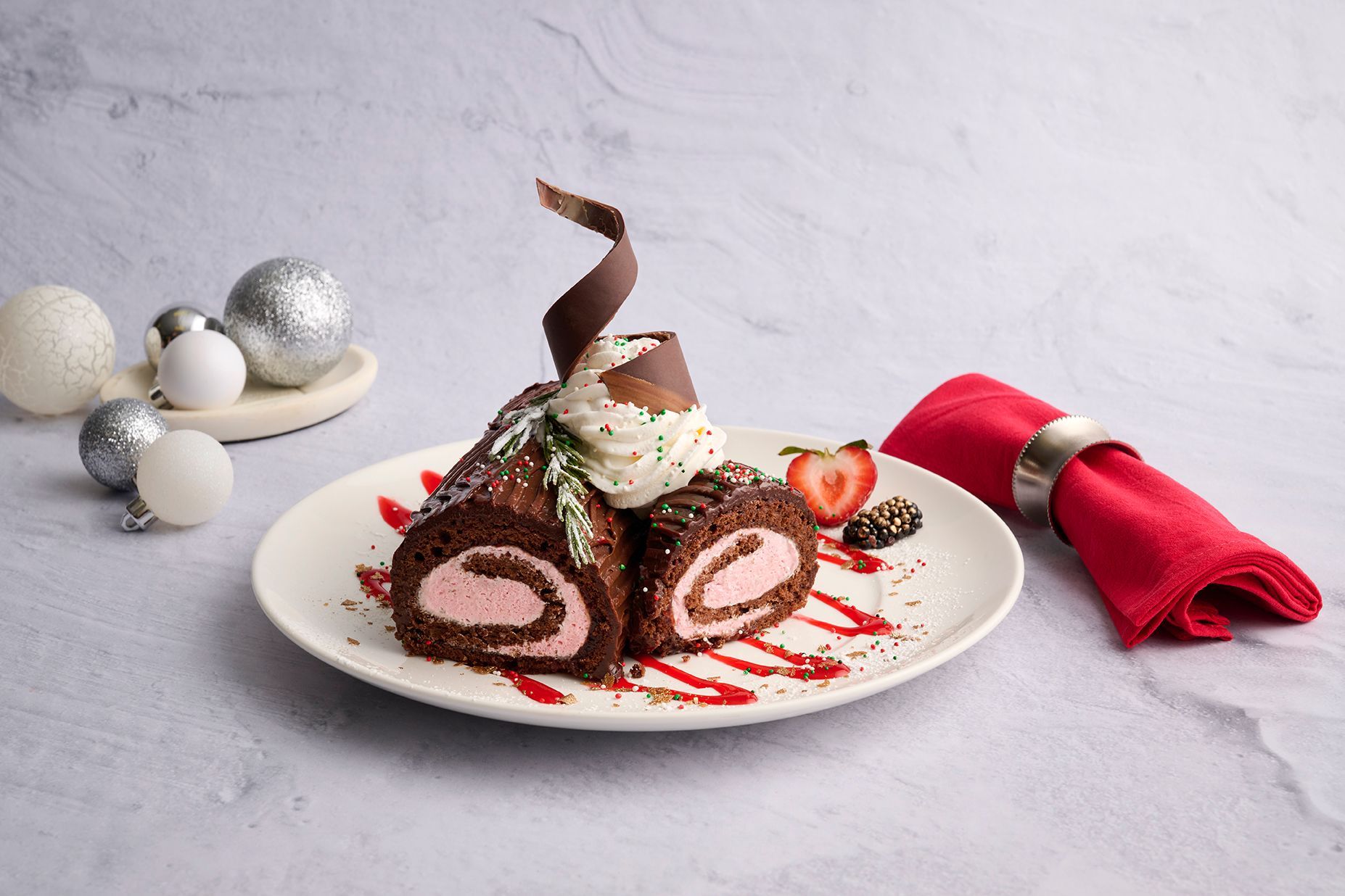 Pumpkin spice cake slice with whipped cream, berries, and sprinkles on a white plate.