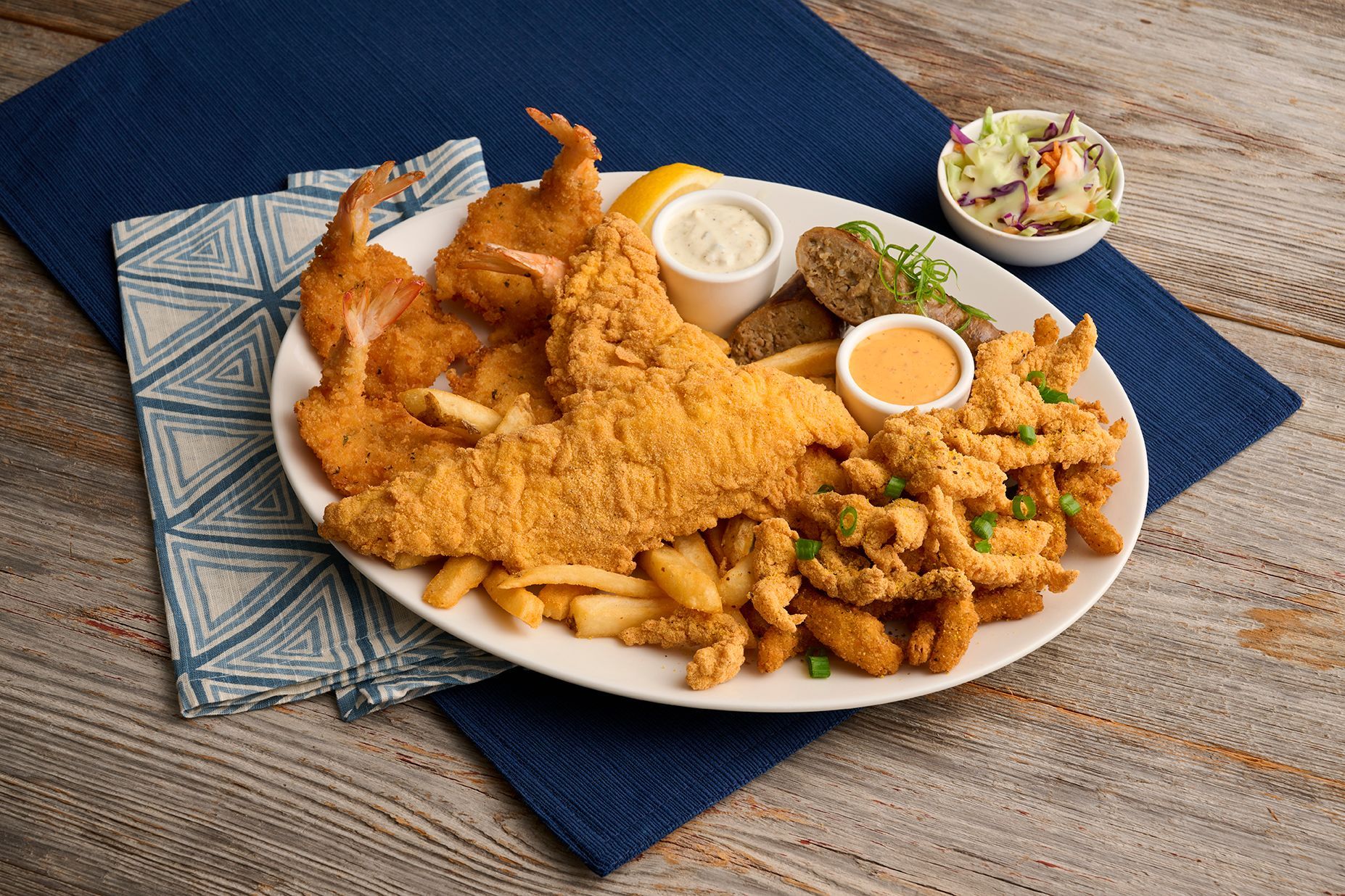 Fried seafood platter with shrimp, fish, clams, fries, and sides.