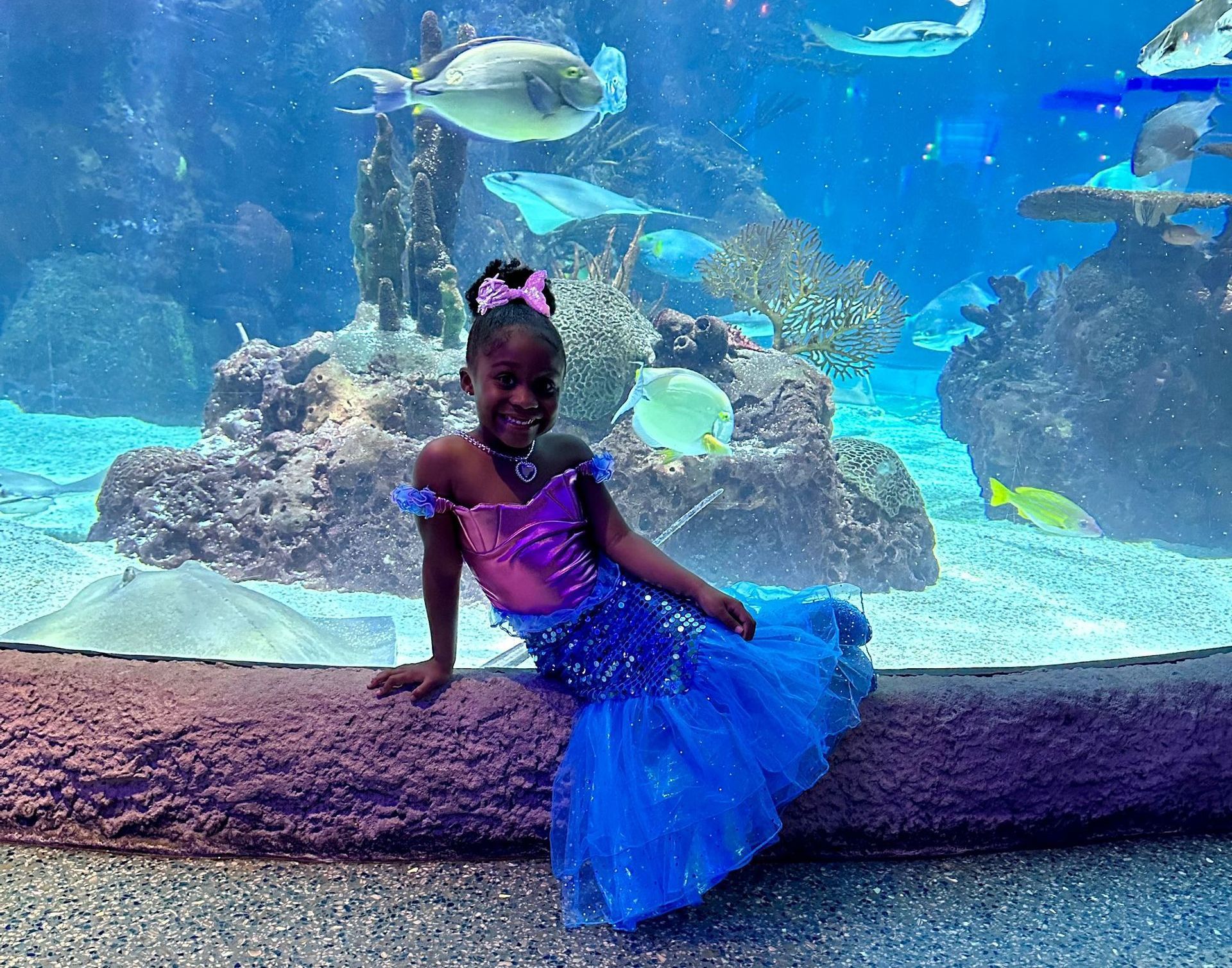 A bride and groom pose in front of an aquarium
