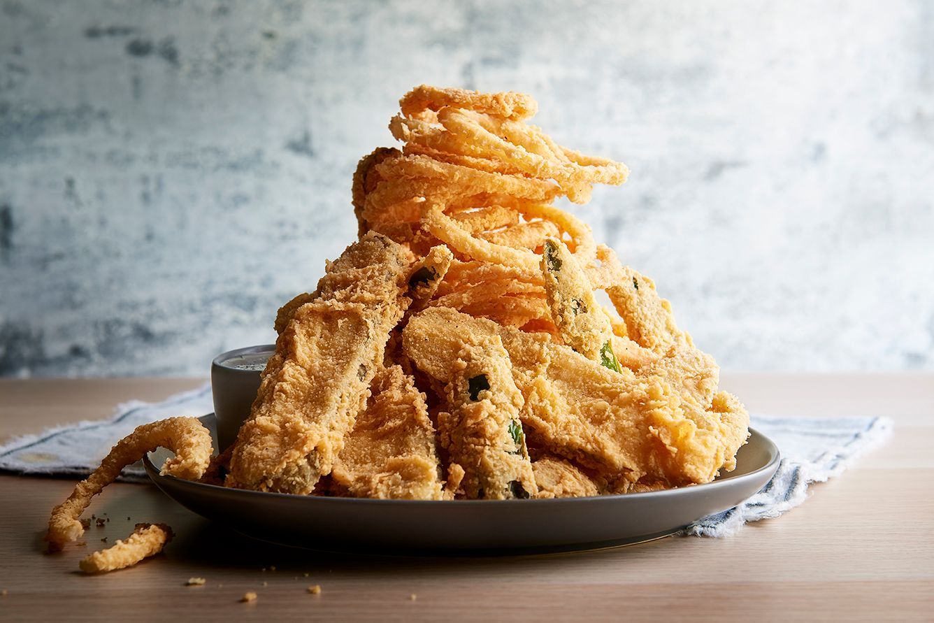 A pile of fried food on a plate with dipping sauce