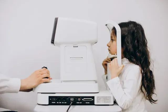 A little girl is getting her eyes checked by an ophthalmologist.