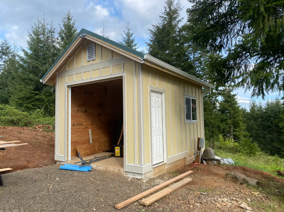 A small shed is being built on top of a dirt hill.