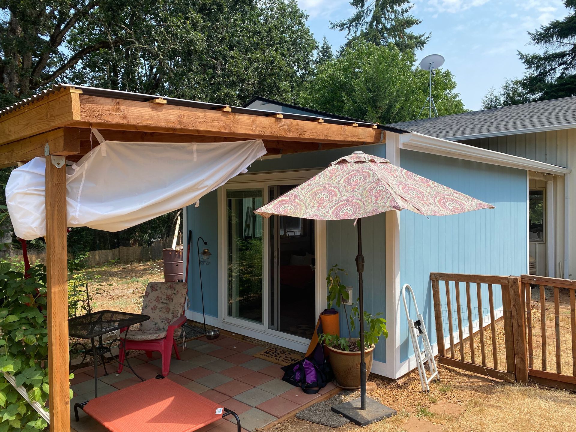 A blue house with a pergola and umbrella in front of it.