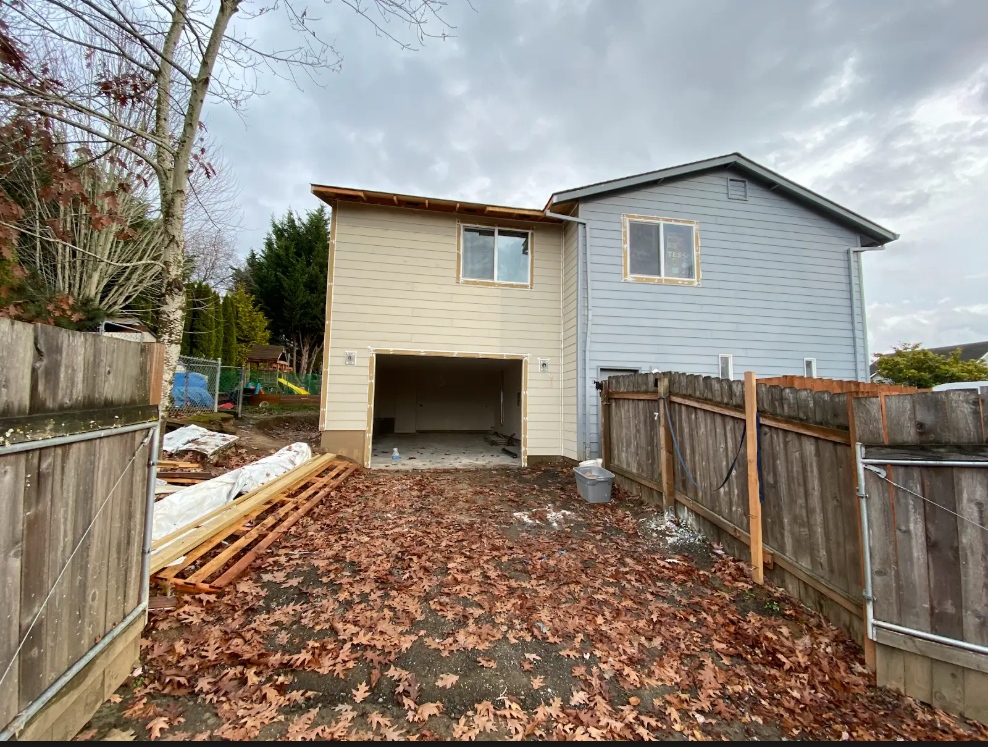 A house with a garage and a fence in front of it.