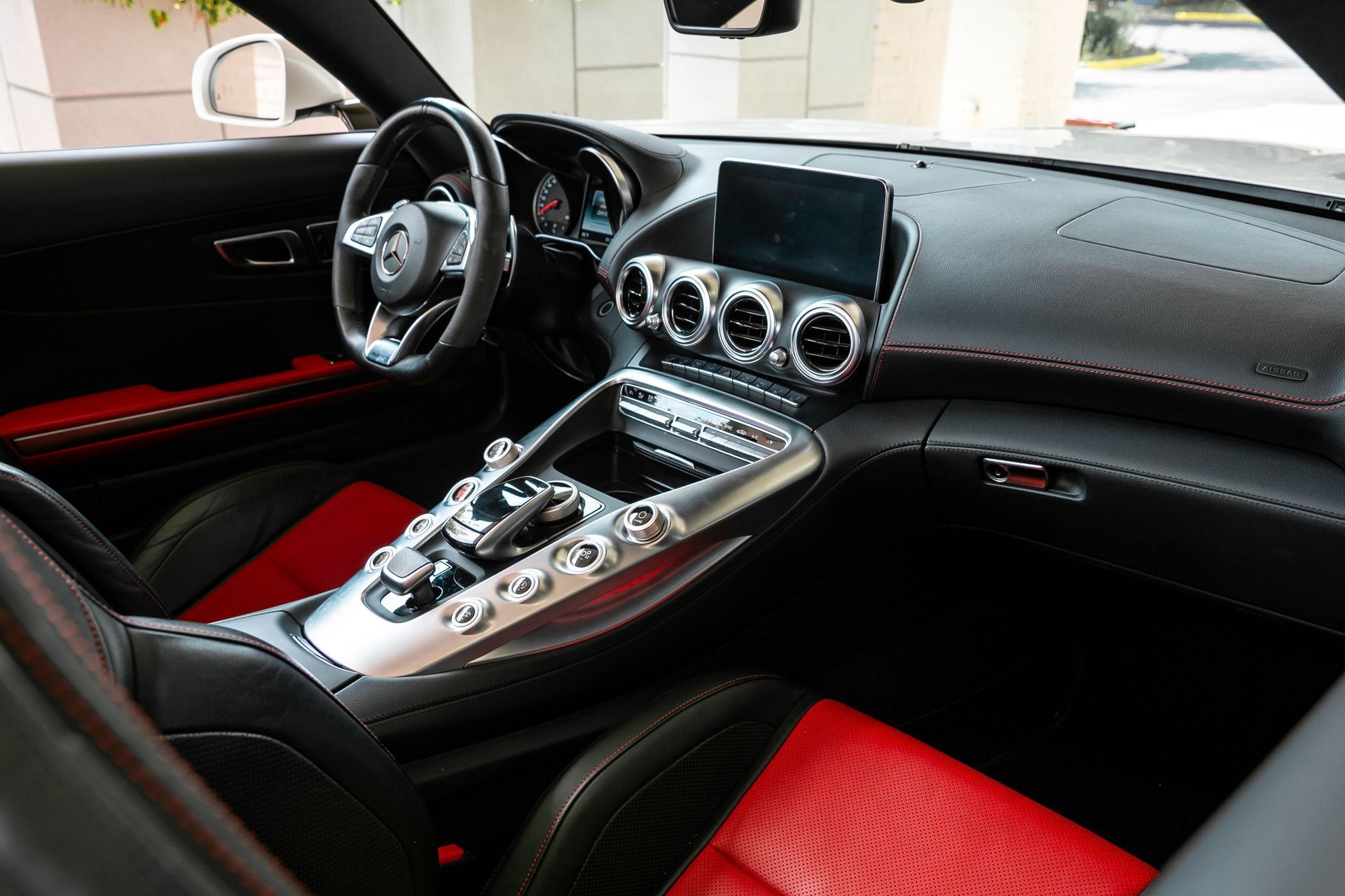 Interior of a black and red Mercedes-AMG sports car. Features include a dashboard, steering wheel, and seats.